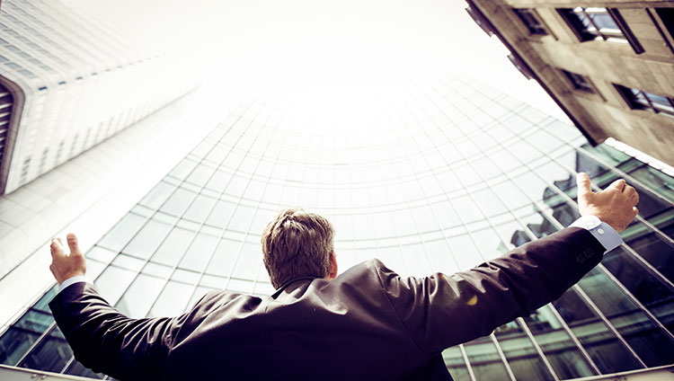 investor with raised hands in front of a business building